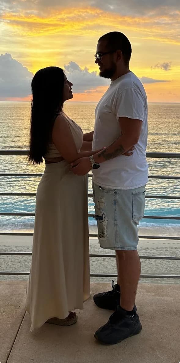 Ariadna y Rogelio tomados de las manos al atardecer, junto al mar
